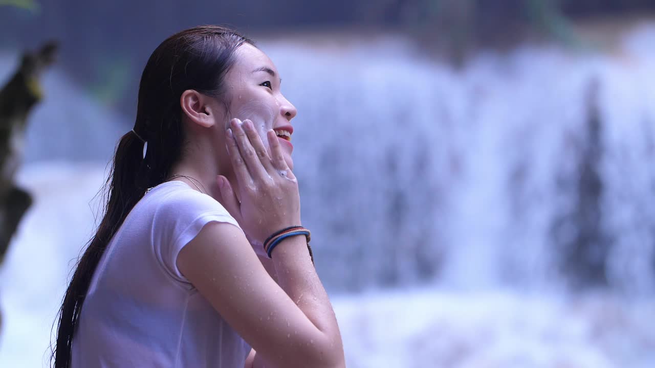 Woman Applying Face Cream by a Waterfall