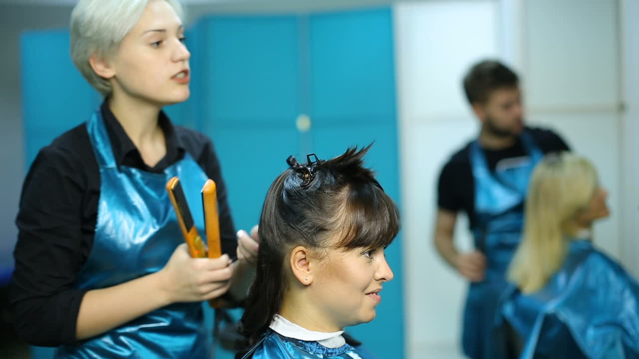 Process of creating hair style. Beautiful woman getting haircut by hairdresser in the beauty salon
