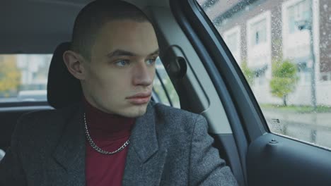 handsome young man waiting inside the car looking through the window - closeup medium shot