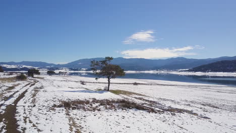 Drone-flies-over-a-lake-with-a-reflection-of-a-mountain-and-sky-in-winter