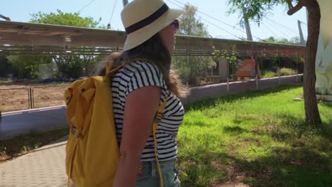 woman traveling with suitcase and backpack in urban green area