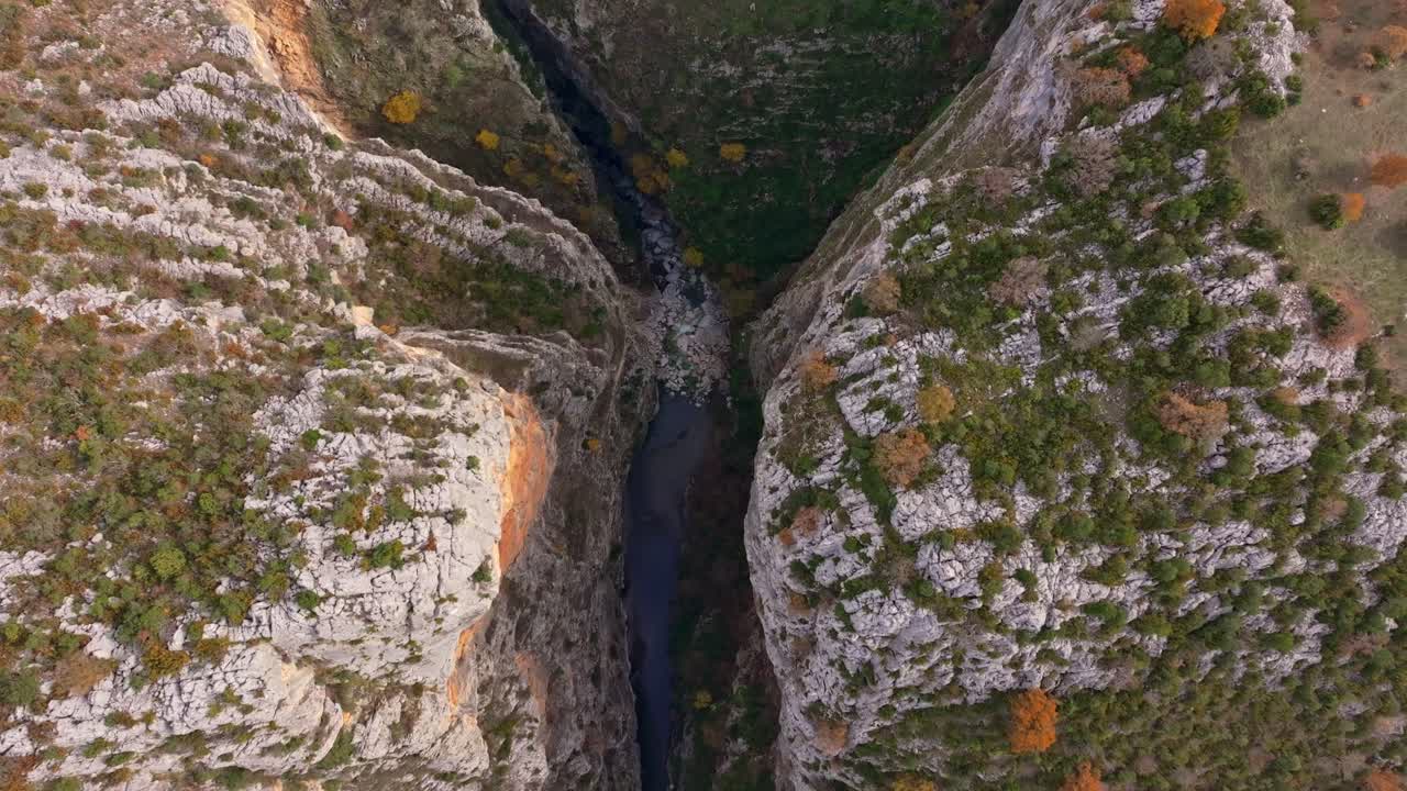 Drohnenaufnahme einer Herbstlandschaft mit Klippen, die eine ruhige Schlucht umrahmen