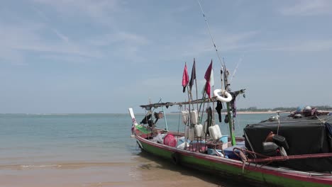 fishing boat with colorful flags on a beach in thailand, takua pa 4k slow motion