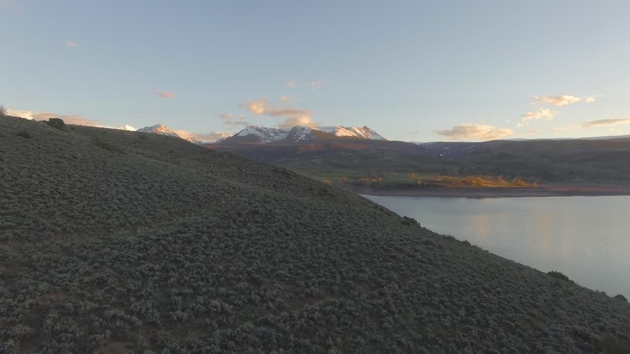 hermosa puesta de sol panoramización a la derecha estableciendo tiro sobre la ladera de la montaña en las montañas rocosas cubiertas de nieve y el lago