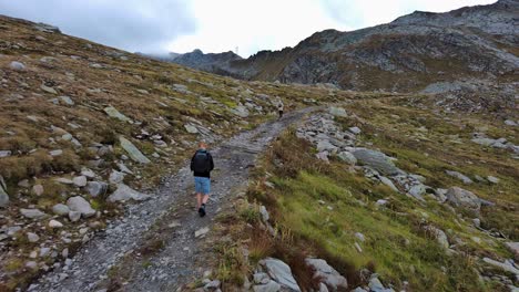 Man-hiking-on-a-path-on-a-hill-with-vegetation-and-rocky