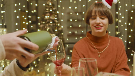 man pouring red wine on her friend's glass