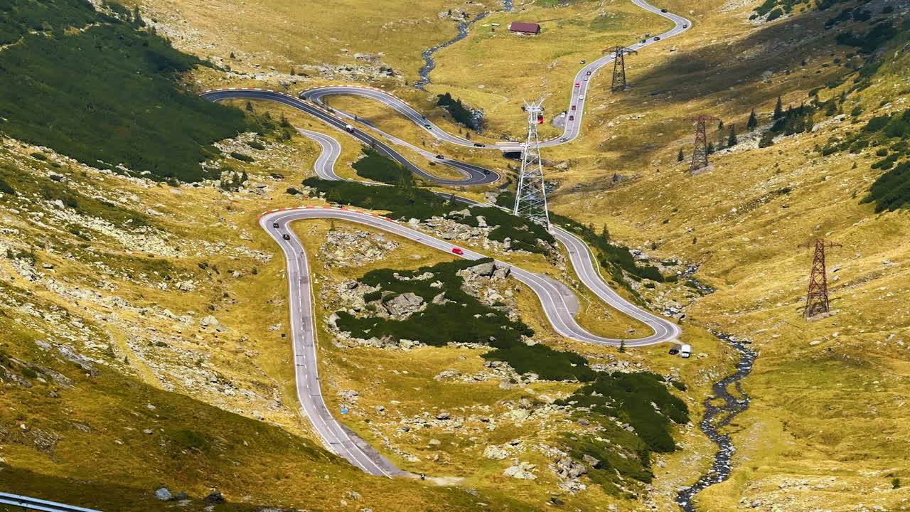 Slowly moving cars by the challenging Transfagarash highway. Drone footage over the valley in the Carpathian Mountains, Romania