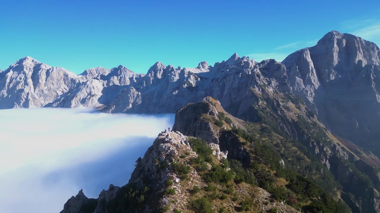Spettacolare ripresa con drone che cattura nuvole drammatiche e alte cime montuose lungo il Passo di Valbona