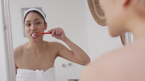 biracial woman with band brushing teeth in bathroom