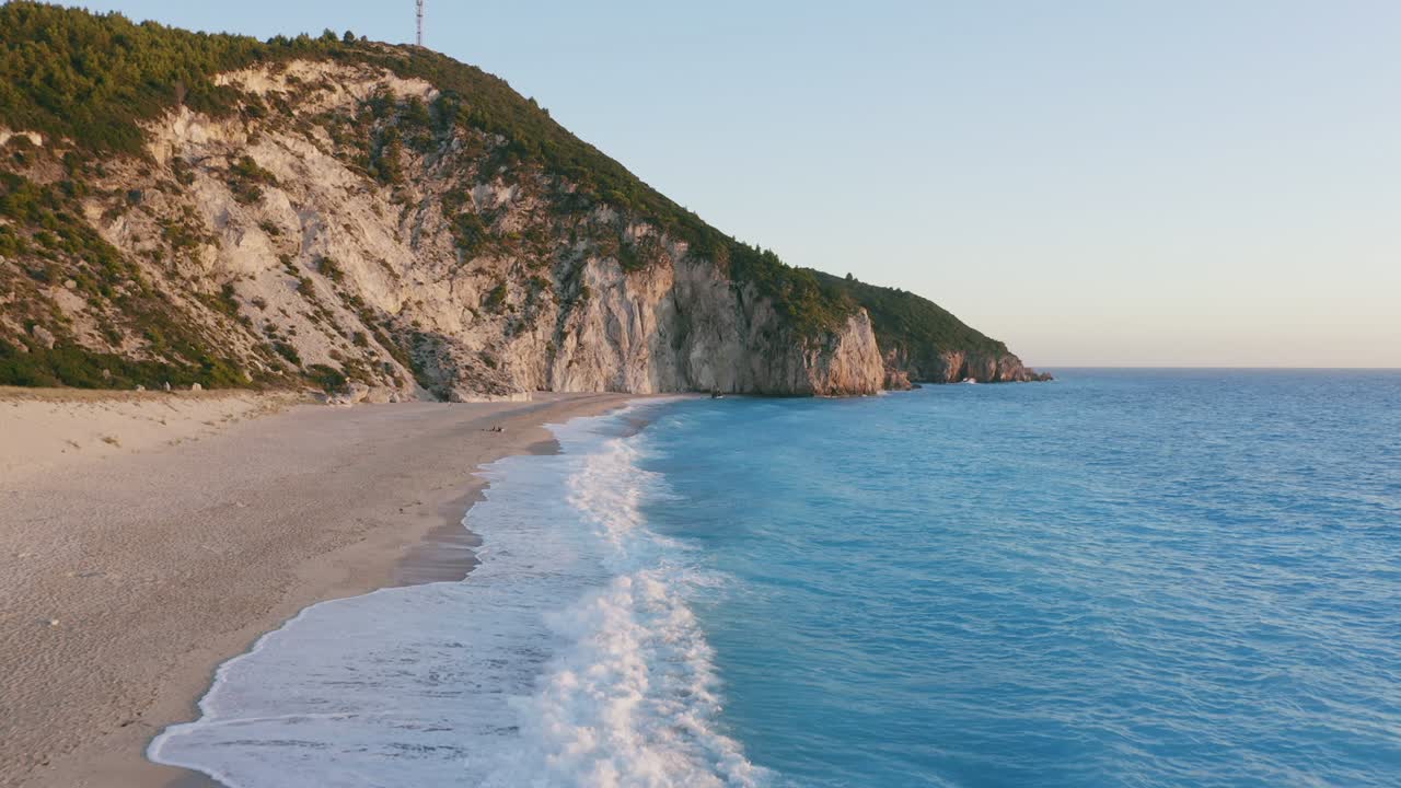 Vista aerea della bellissima spiaggia di Milos a Lefkada, isola ionica, Grecia. Luce solare dorata del tramonto e onde incontaminate che si infrangono sul mare blu turchese a riva.