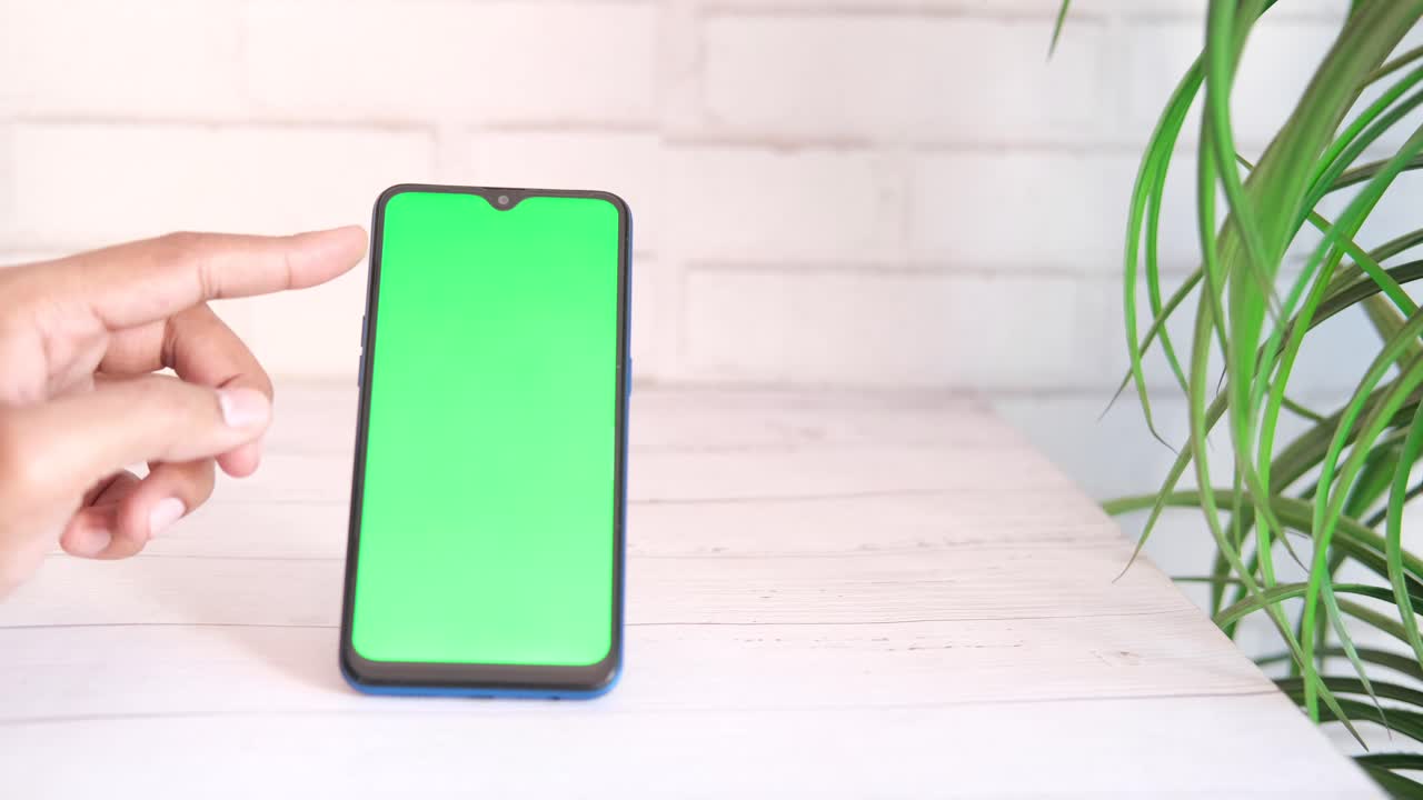 mano tocando un teléfono inteligente con pantalla verde