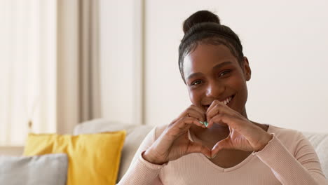 happy young woman making a heart shape with hands