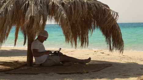 Mann-Benutzt-Laptop-Am-Strand