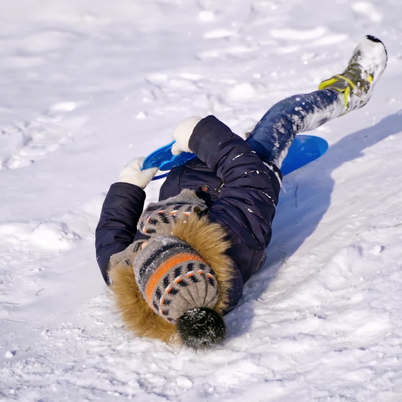 Child boy having fun, playing on a snowy winter walk in nature. Frost winter season.Cute little boy with plastic sledges walks up a hill.
