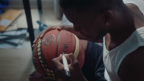 basketball player signing a ball at home