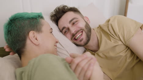 feliz pareja joven hablando y riendo juntos mientras están acostados en la cama