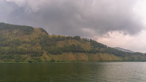 overcast sky over a serene lake and forested hills