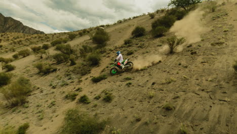 motorcyclist rides downhill with dust trail fpv. skilled rider maneuvers modern vehicle across offroad area at racing. sense of power and freedom