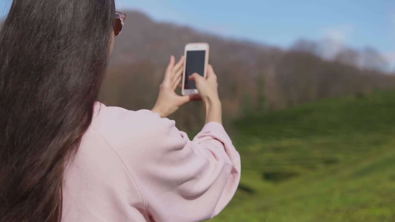 mujer tomando una foto de una plantación de té