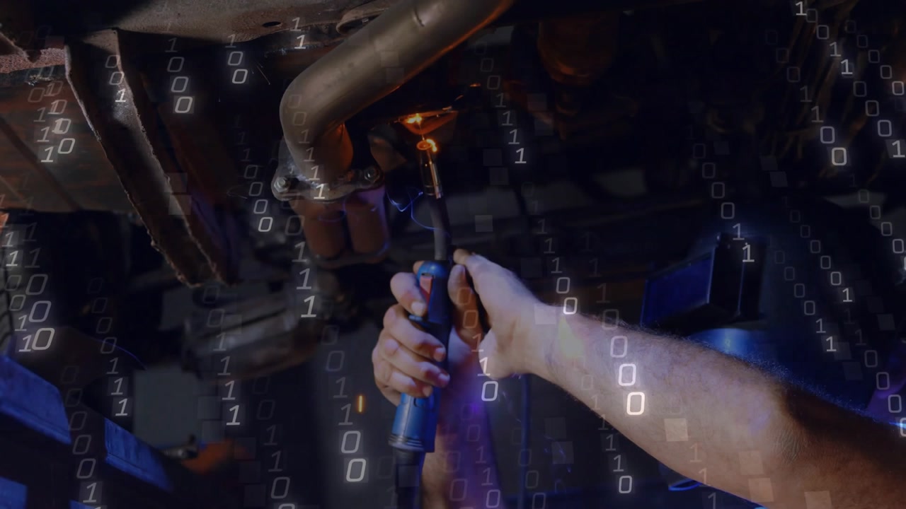 Mechanic lying on creeper in workshop holding torch igniting arc welding exhaust pipe for repair