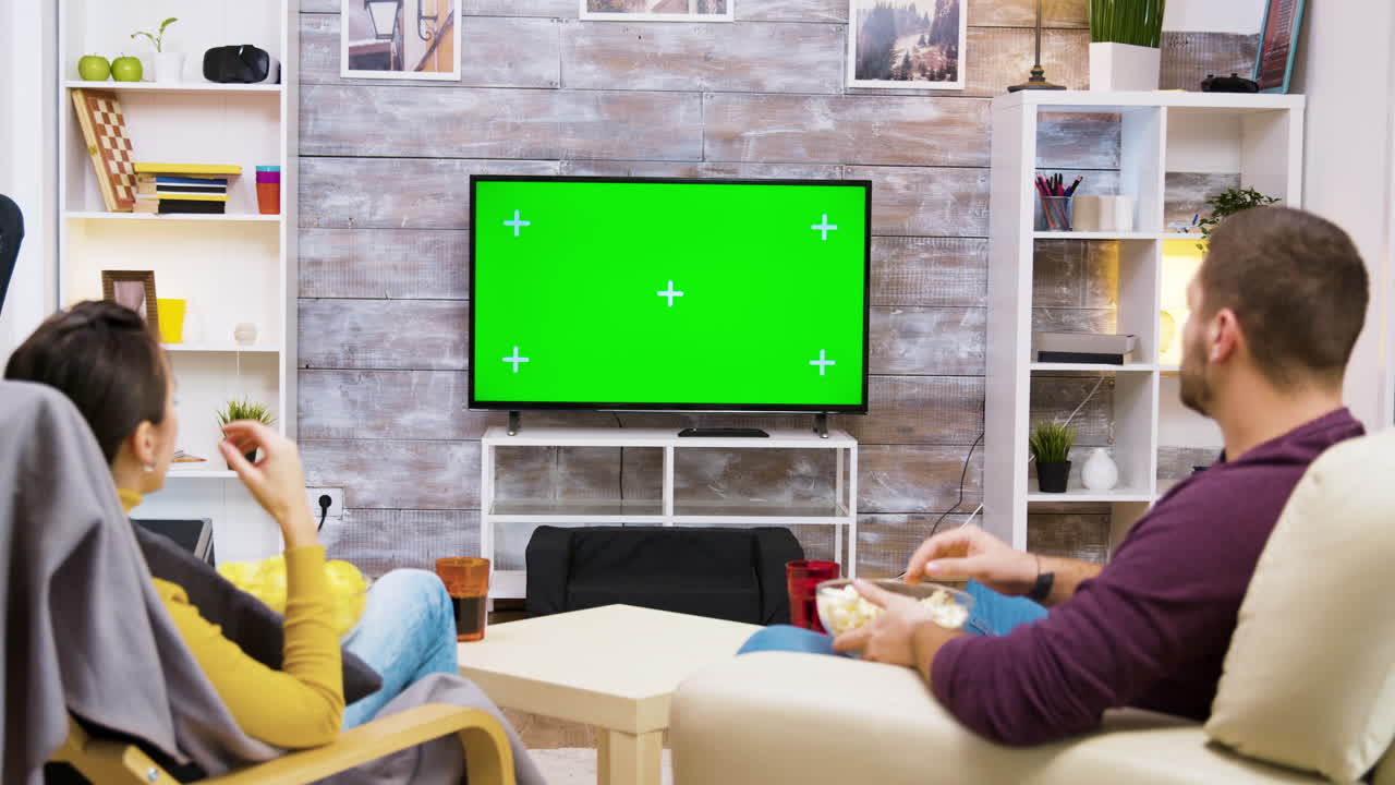 Couple watching TV with green screen in living room