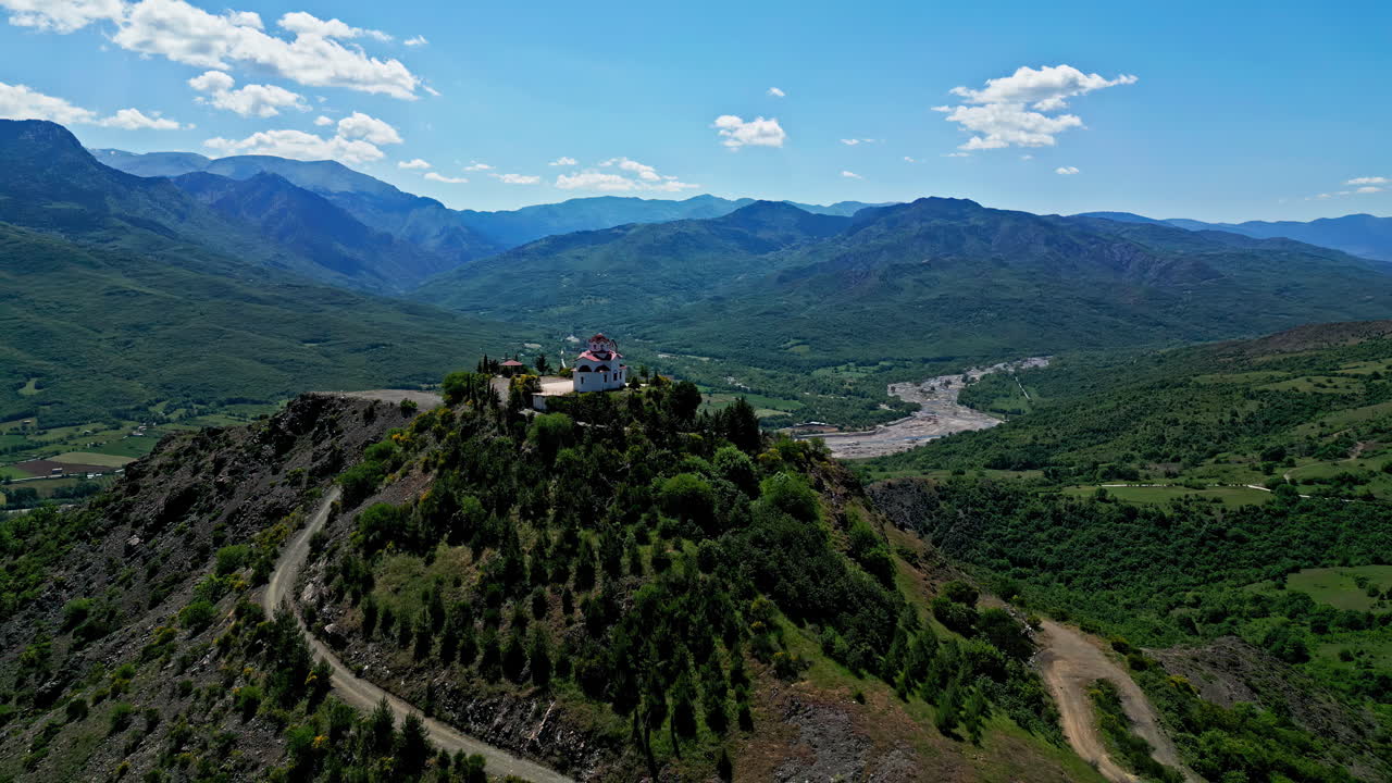 Atemberaubende griechische Landschaft mit einer kleinen, weißen Kapelle auf einem Hügel mit Blick auf ein üppiges, grünes Tal