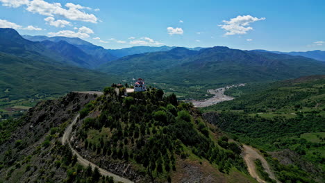 Breathtaking Greek landscape as small, white chapel sits atop a hill overlooking lush, green valley