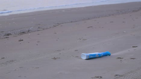 blue plastic bottle on the beach, trash and waste litter on an empty baltic sea white sand beach, environmental pollution problem, calm evening, medium shot