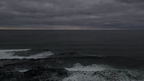 drone shot flying backwards over a lighthouse on a moody dramatic morning or evening overlooking the ocean