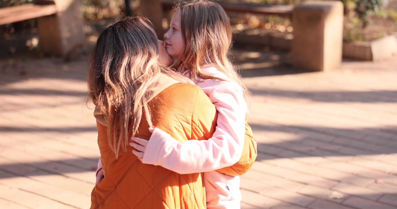 Momento tenero tra donna e bambina che si abbracciano e si baciano