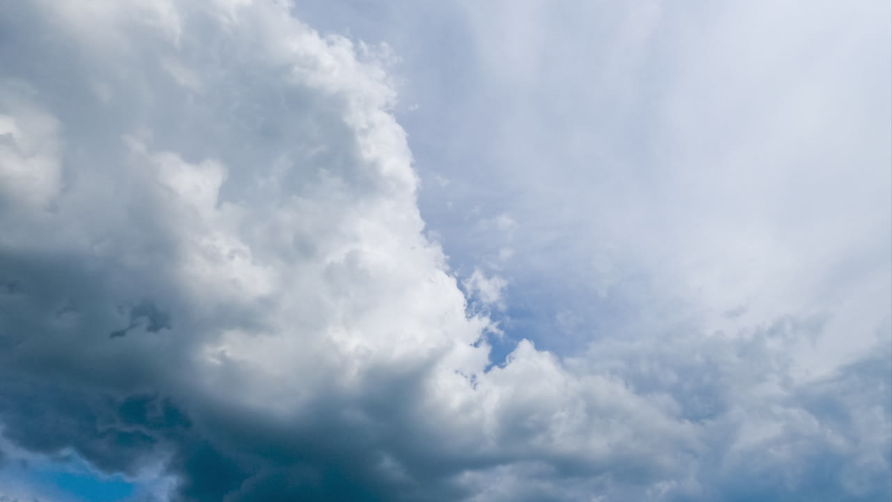Grey cumulus clouds transforming in atmosphere. Heavy clouds go away and light spindrift clouds extending by the blue sky. Timelapse.