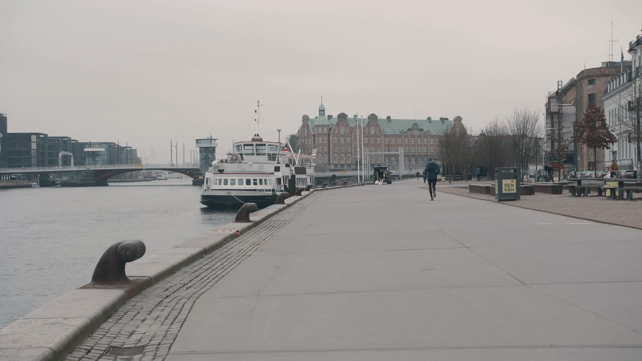 hombre trotando en la costa de copenhague en un entorno urbano vistas de la propiedad frente al mar mientras corre hacia la distancia