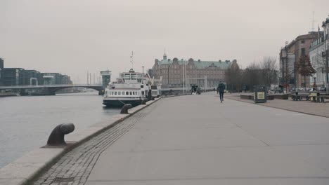 hombre trotando en la costa de copenhague en un entorno urbano vistas de la propiedad frente al mar mientras corre hacia la distancia