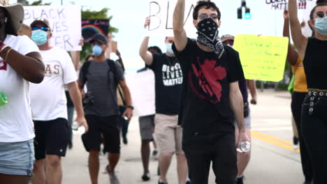 crowd of protestors holding up banners walking past camera at black lives matter protest