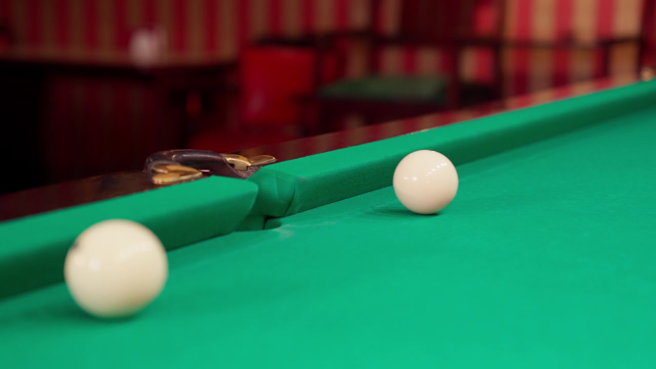 Close-up van een biljartbal die in een gat verdwijnt op een groene tafel