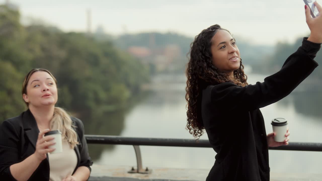 Friends Taking Selfies and Enjoying Coffee Outdoors on a Bridge