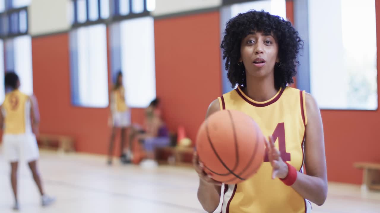 retrato de una jugadora de baloncesto afroamericana sosteniendo la pelota en una cancha cubierta, en cámara lenta