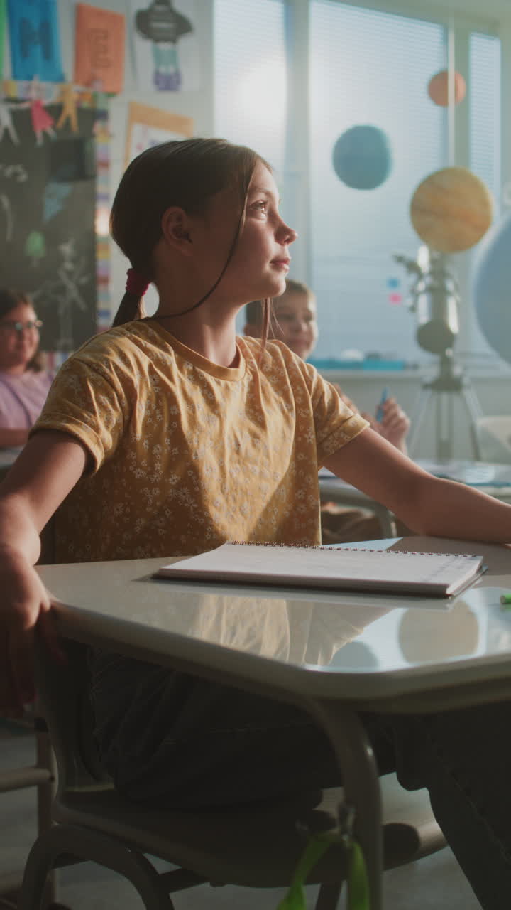 Primary School Children Sitting at Desks Writing School Exam or Doing Tasks in Notebooks
