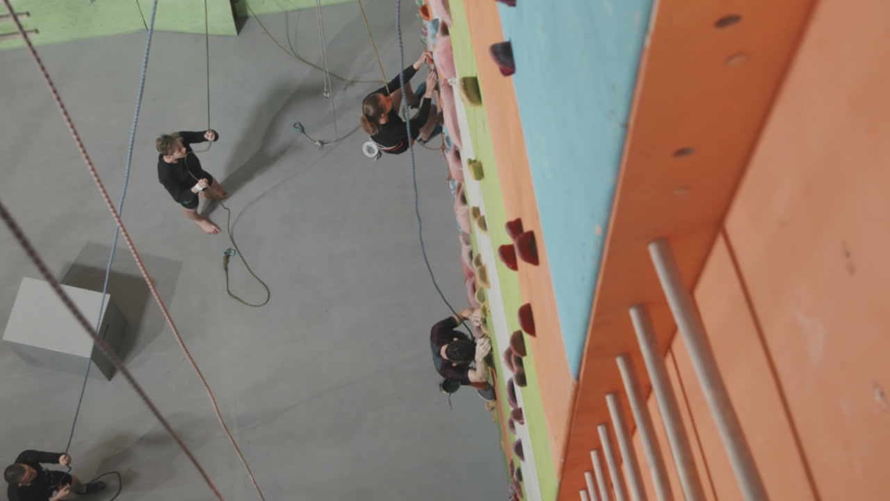 Top-View Of People Climbing Wall Indoors At Sports Complex