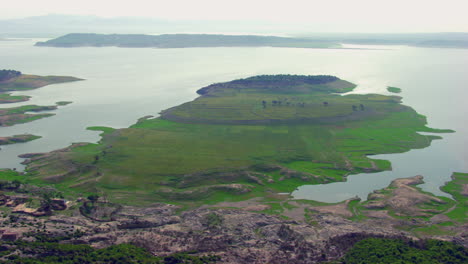 Hermosa-Vista-Aérea-De-Irlanda-Con-Sol-En-El-Agua,-Hierba-Verde-En-La-Tierra,-Casas-Antiguas-Y-árboles