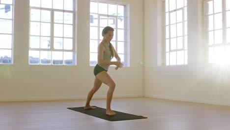 healthy-yoga-woman-practicing-warrior-pose-enjoying-fitness-lifestyle-exercising-in-workout-studio-stretching-training-on-exercise-mat-at-sunrise