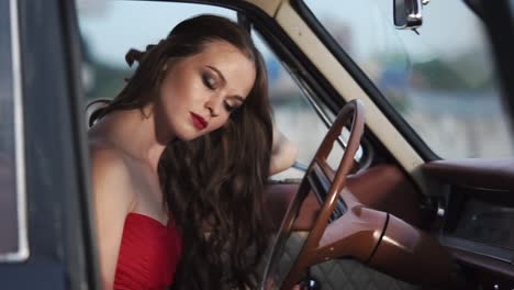 woman in a red dress driving a vintage car
