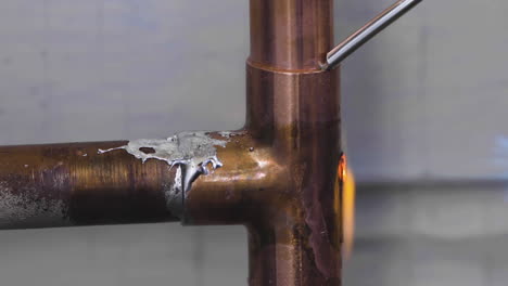 Liquid-solder-welds-together-copper-pipes-while-a-blowtorch-heats-the-metal