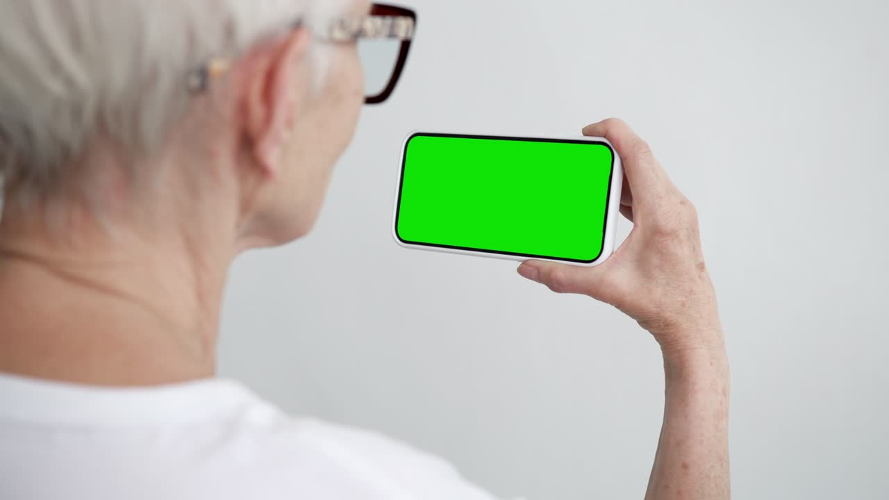노인 터치 스크린 스마트폰 녹색 크로마 키 클로즈업 50대 여성 손에 드폰을 들고 클릭하는 모형 컨셉 시청 및 인터넷 쇼 소셜 미디어, 뉴스 읽기, 앱 전자 쇼핑 4k