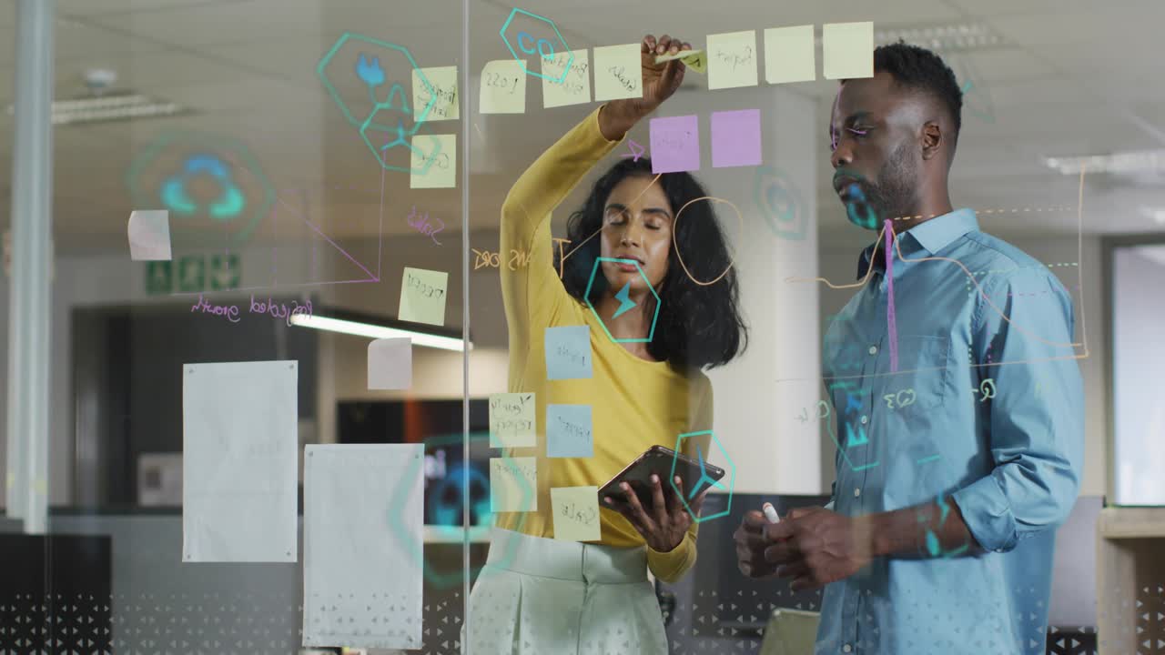 Woman checking tablet and placing sticky notes on glass, man watching and marking for business