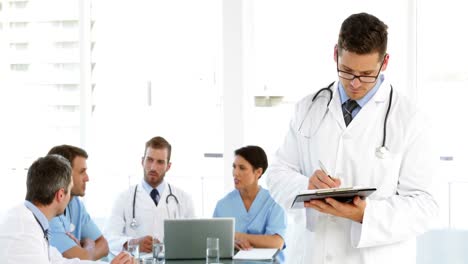 médico pensativo con el personal hablando detrás de él
