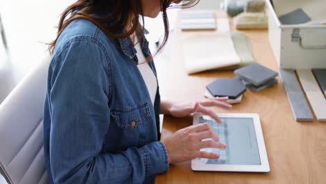 ejecutiva sentada en un escritorio y usando una tableta digital