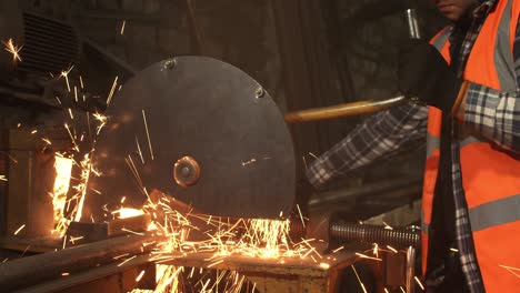 trabajador masculino cortando metal en un taller sucio