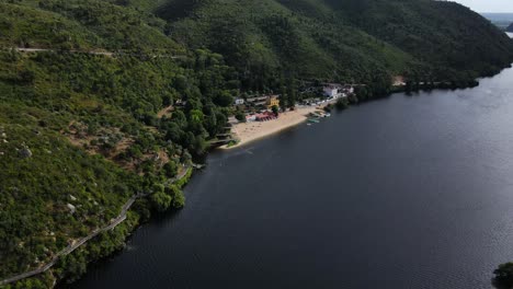 Vista-Aérea-De-Una-Asombrosa-Playa-Fluvial-De-Montaña-Con-Arena-Clara-Y-Algunas-Casas