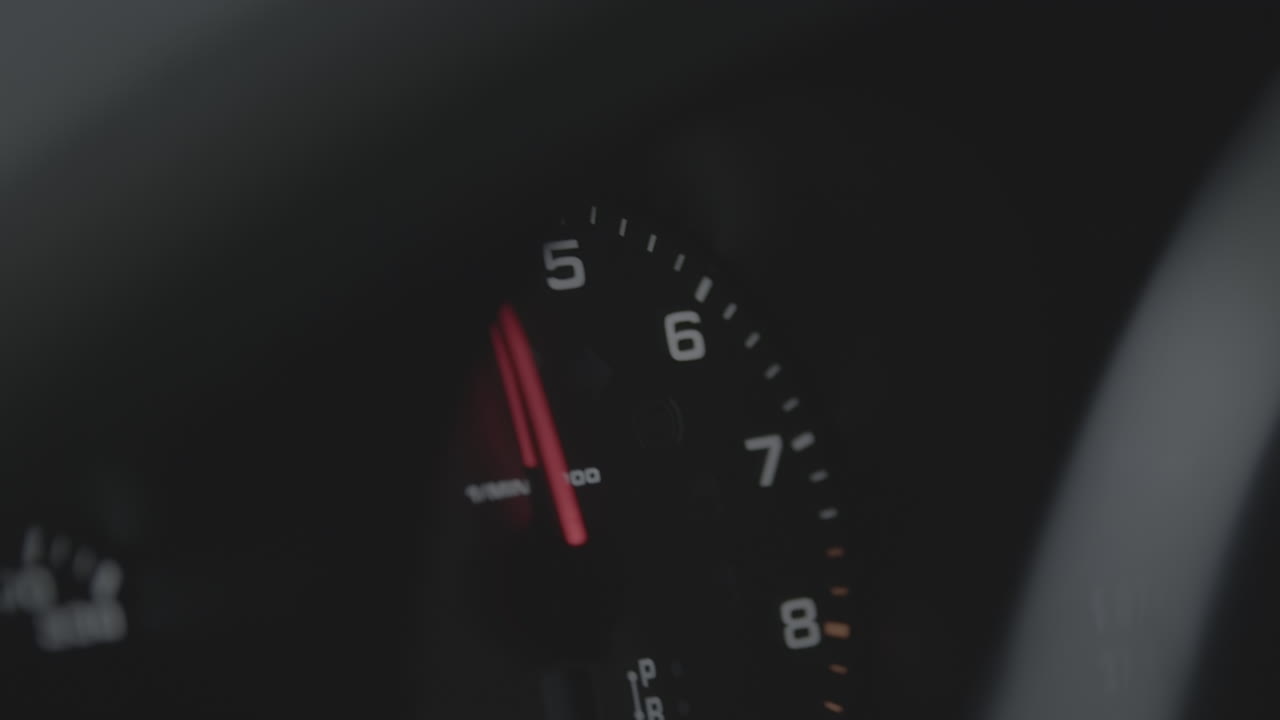 Close up shot of a speedometer in a car revving up and down with a red arrow LOG